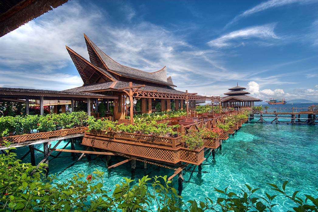 Water bungalows on stilts over shallow turquoise water at Mabul Island